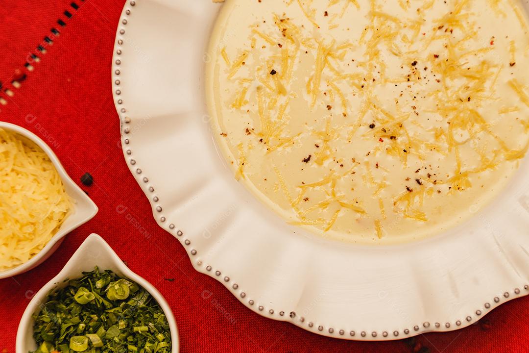 Delicioso e saboroso Caldo de Mandioca, caldo de batata, caldo com queijo ralado por cima e salsa