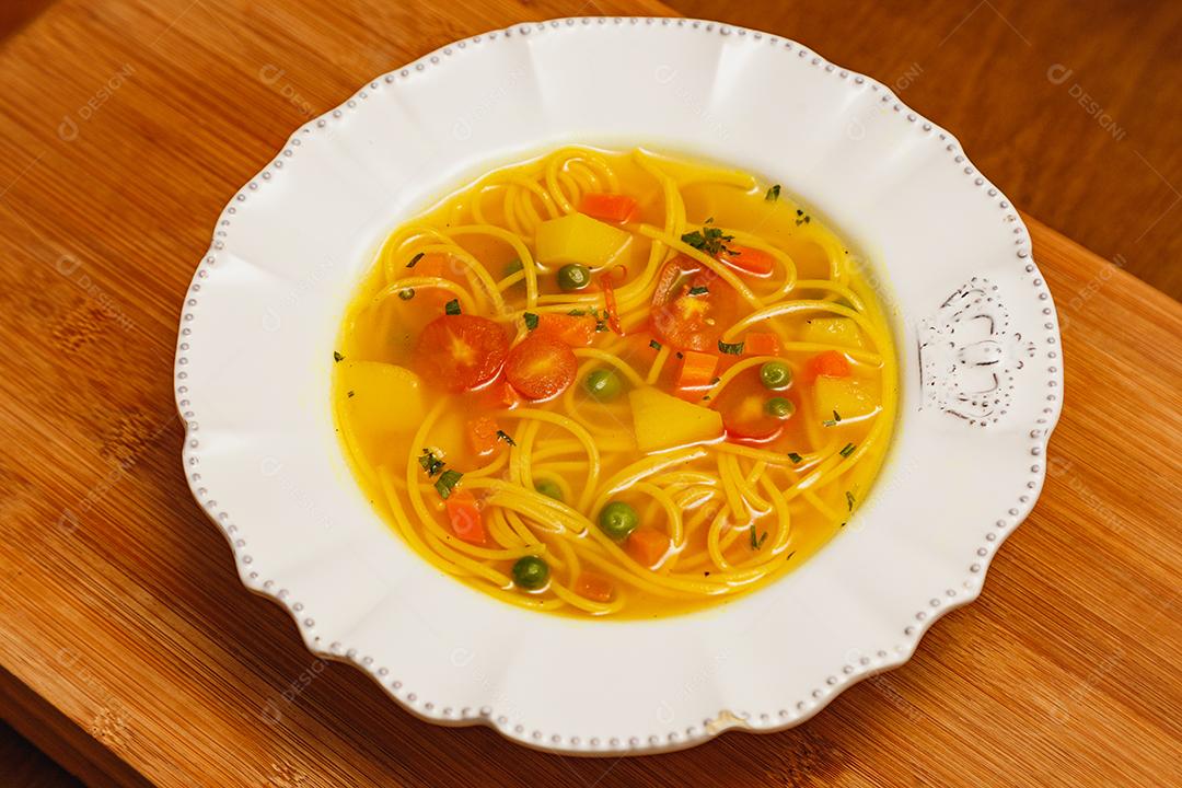 Deliciosa sopa de macarrão com legumes, sopa de macarrão com legumes, em um fundo de madeira