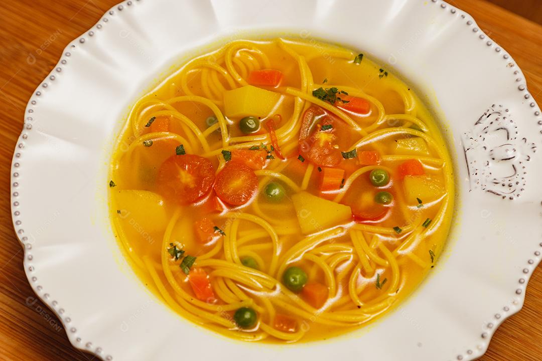 Deliciosa sopa de macarrão com legumes, sopa de macarrão com legumes, em um fundo de madeira