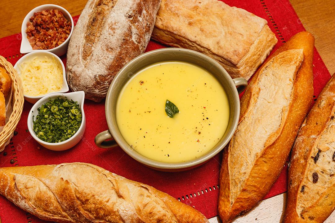 Delicioso caldo de batata ou mandioca, sopa de batata ou mandioca, vegetariano, salsa, com fundo de madeira e tecido vermelho