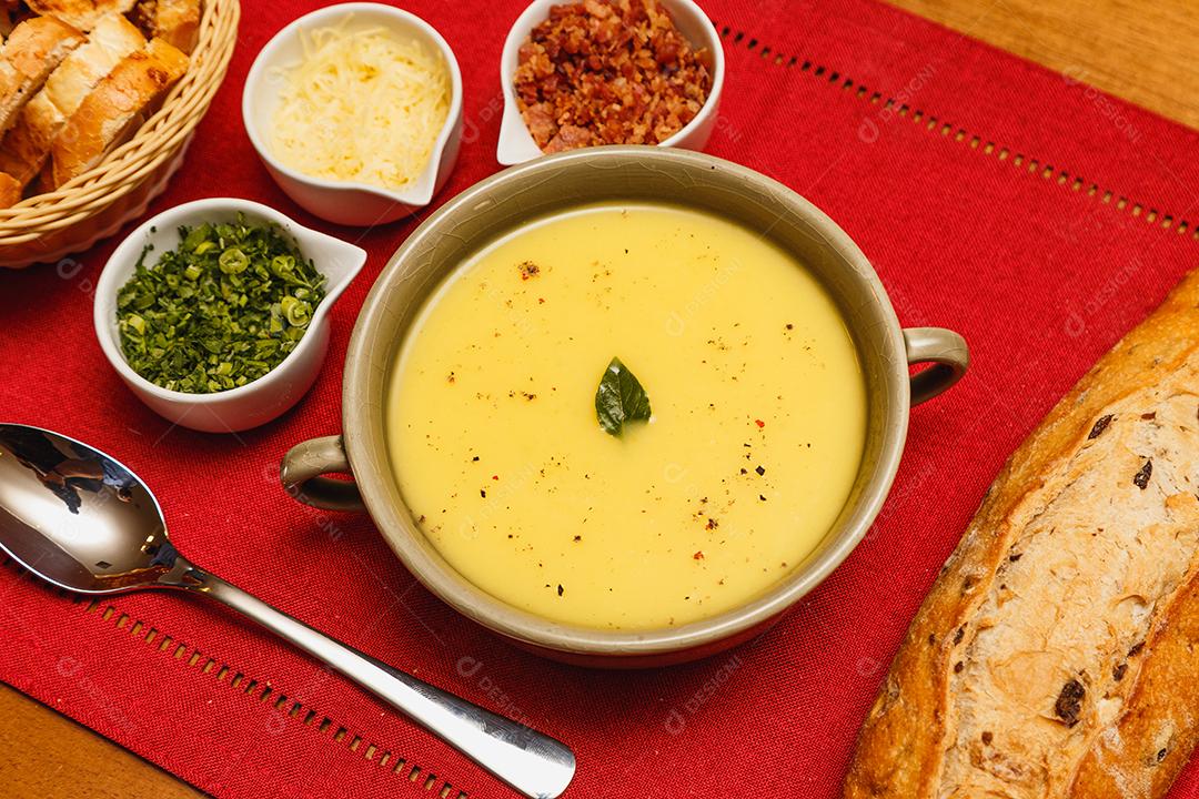 Delicioso caldo de batata ou mandioca, sopa de batata ou mandioca, vegetariano, salsa, com fundo de madeira e tecido vermelho