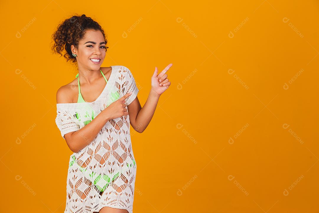 Mulher com roupa de praia e biquini verde por baixo em fundo verde