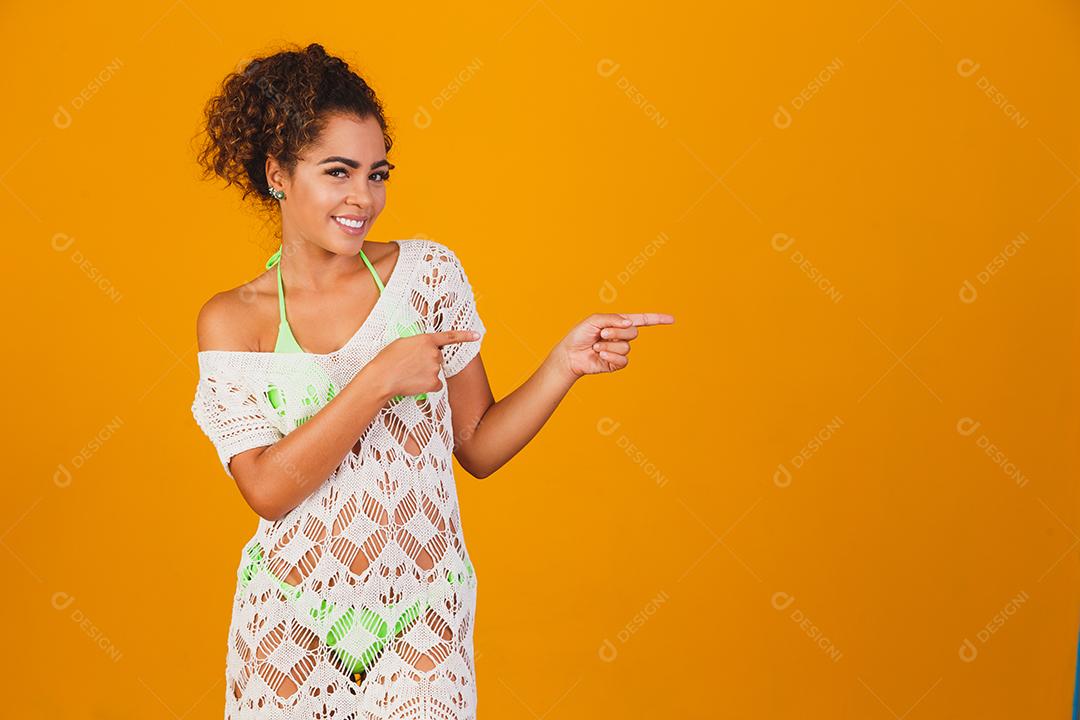 Mulher com roupa de praia e biquini verde por baixo em fundo verde