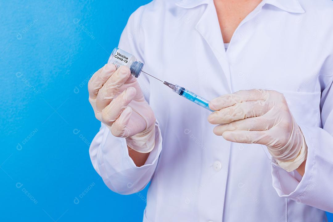 Mulher médica com jaleco e estetoscópio segurando agulha em fundo azul