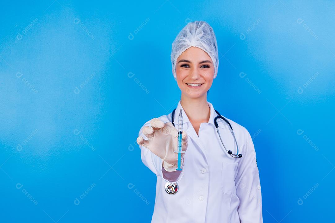 Mulher médica com jaleco e estetoscópio segurando agulha em fundo azul