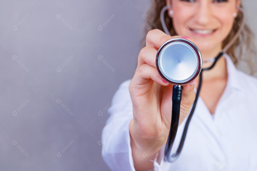 Mulher médica com jaleco e estetoscópio em fundo cinza