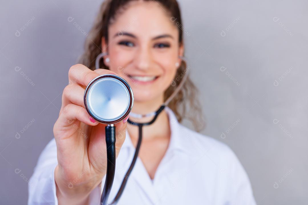 Mulher médica com jaleco e estetoscópio em fundo cinza