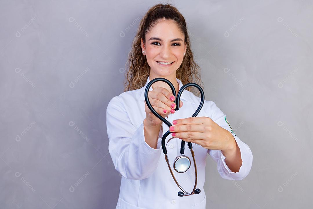 Mulher médica com jaleco e estetoscópio em fundo cinza