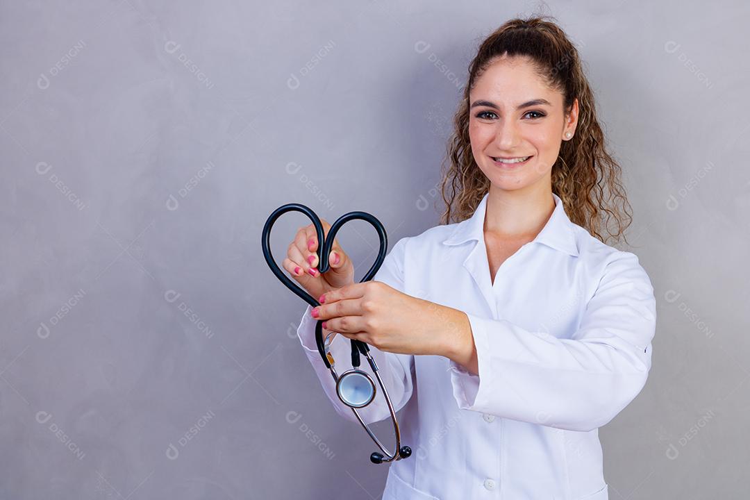 Mulher médica com jaleco e estetoscópio em fundo cinza