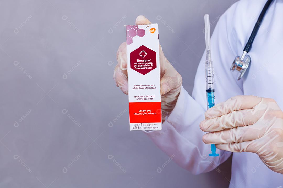 Mulher médica com jaleco e estetoscópio segurando vacina em fundo cinza