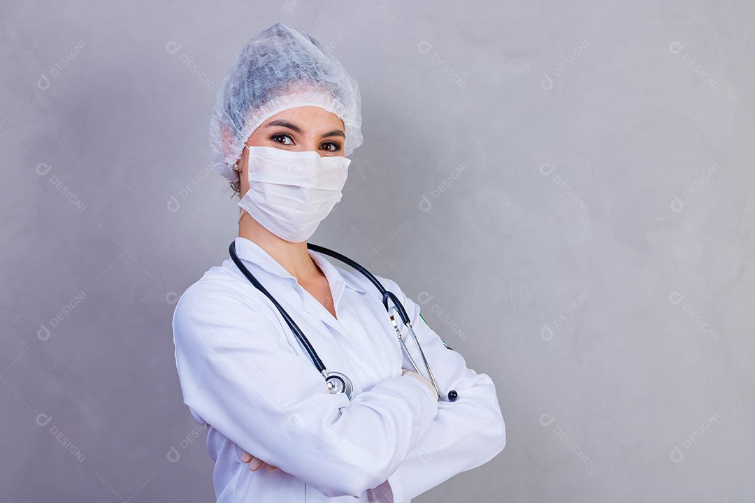 Mulher médica com jaleco e estetoscópio em fundo cinza