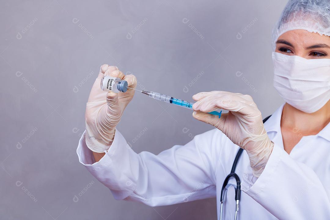 Mulher médica com jaleco e estetoscópio segurando vacina em fundo cinza