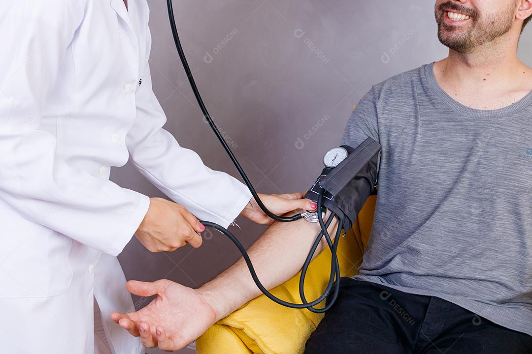 Mão do médico medindo a pressão arterial do paciente do sexo masculino