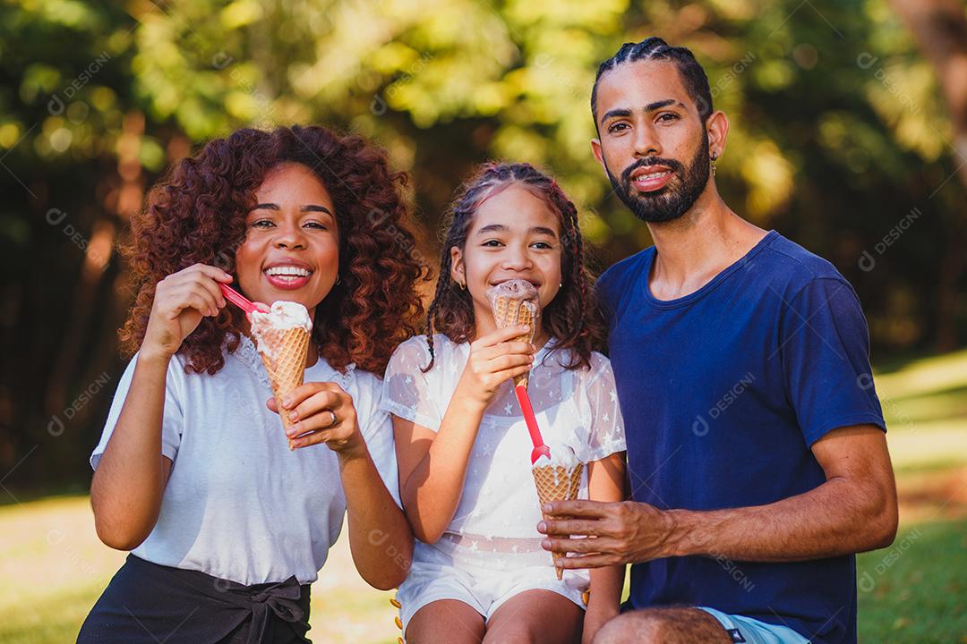 Família tomando sorvete em praça gramada em dia ensolarado