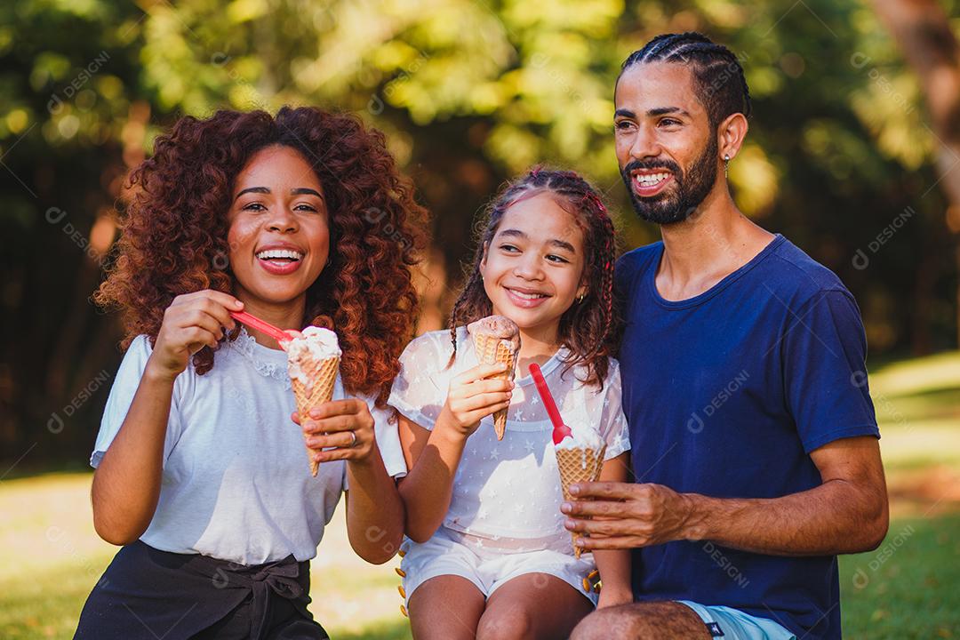 Família tomando sorvete em praça gramada em dia ensolarado