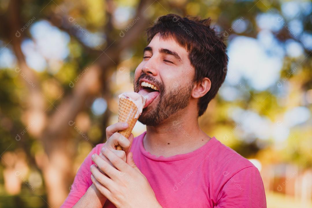 jovem bonito comendo sorvete no parque