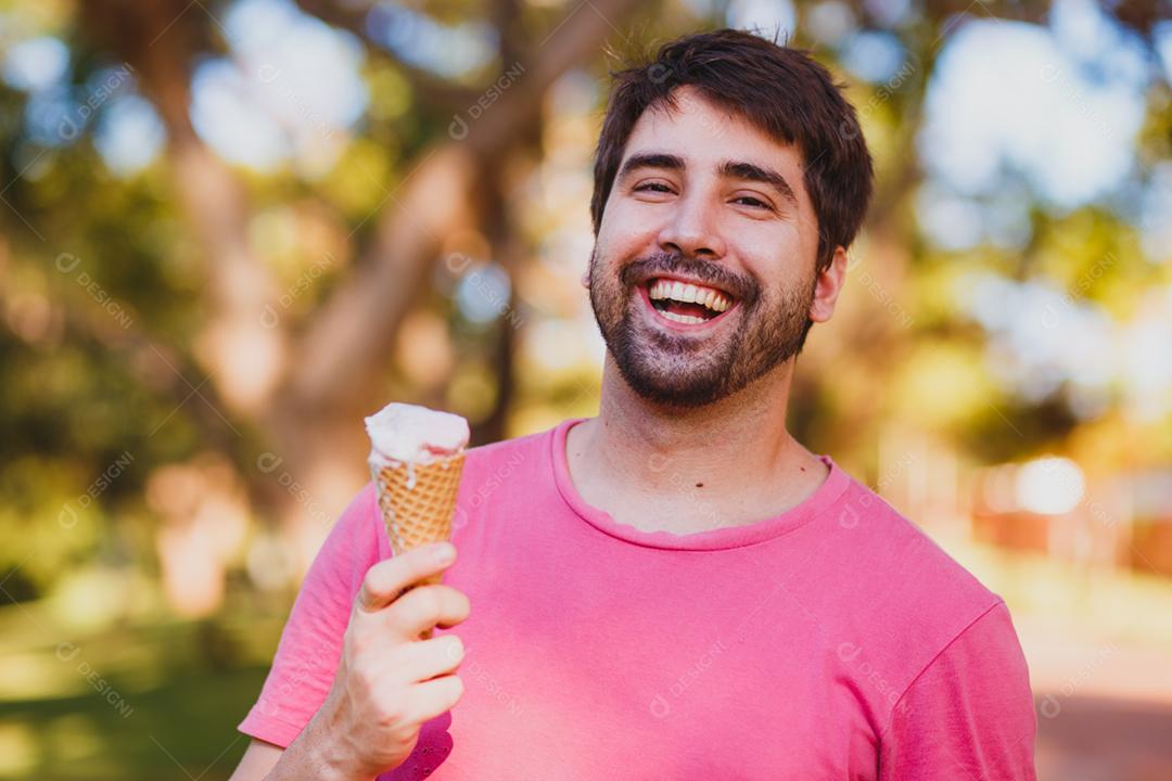 jovem bonito comendo sorvete no parque