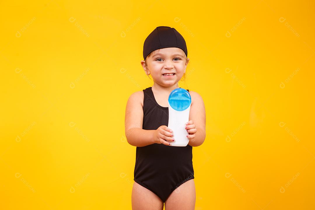 Menina com maiô de natação e protetor solar.