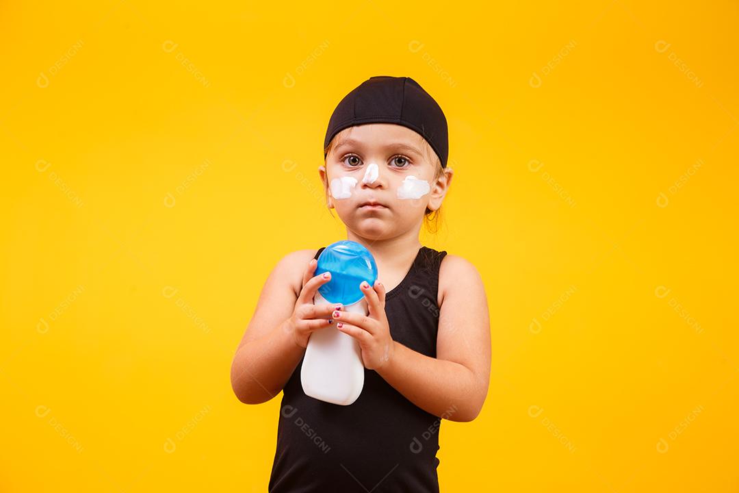 Menina com maiô de natação e protetor solar.