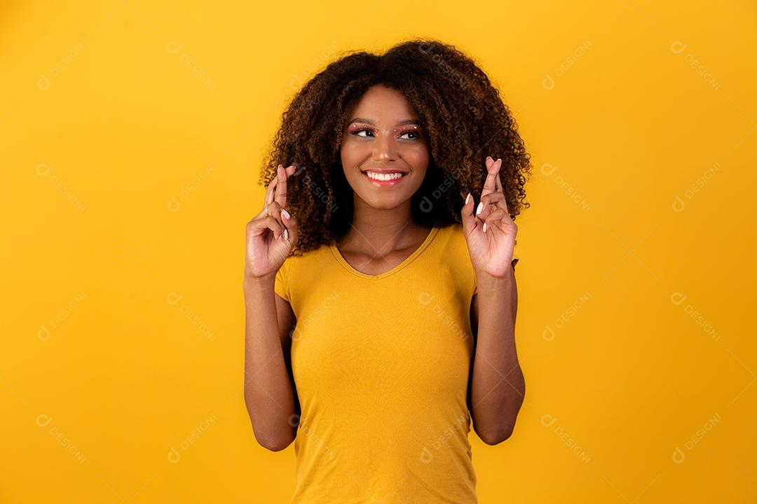 mulher afro com os dedos cruzados torcendo pela vitória