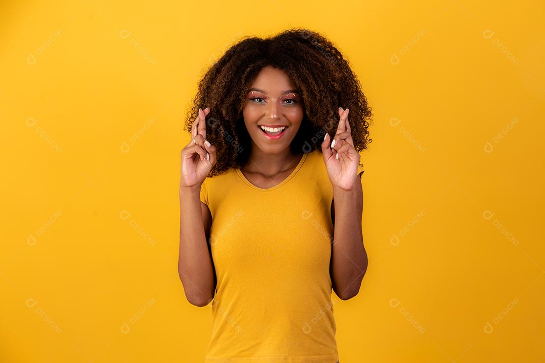 mulher afro com os dedos cruzados torcendo pela vitória