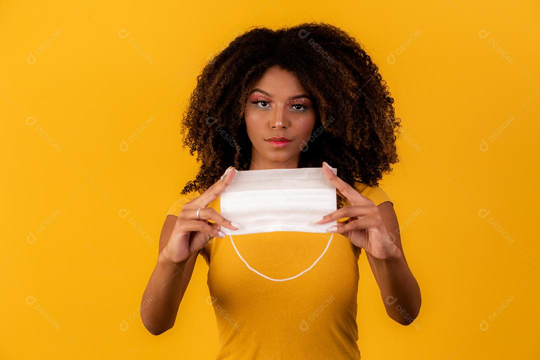 jovem afro segurando máscara protetora na pandemia de coronavírus, covid-19