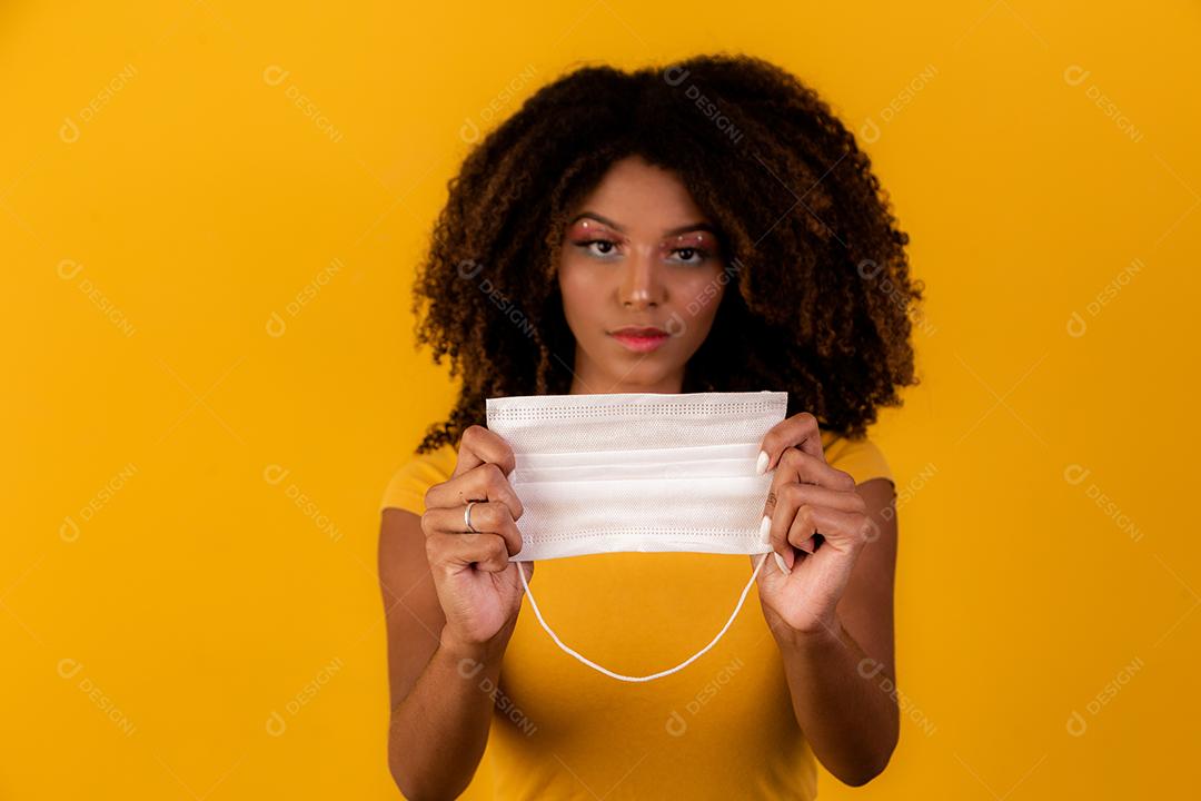 jovem afro segurando máscara protetora na pandemia de coronavírus, covid-19