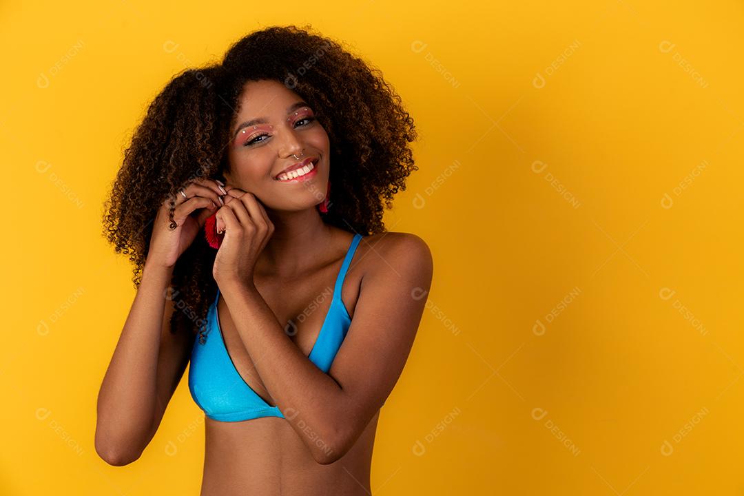 linda mulher afro sorridente colocando brincos na orelha