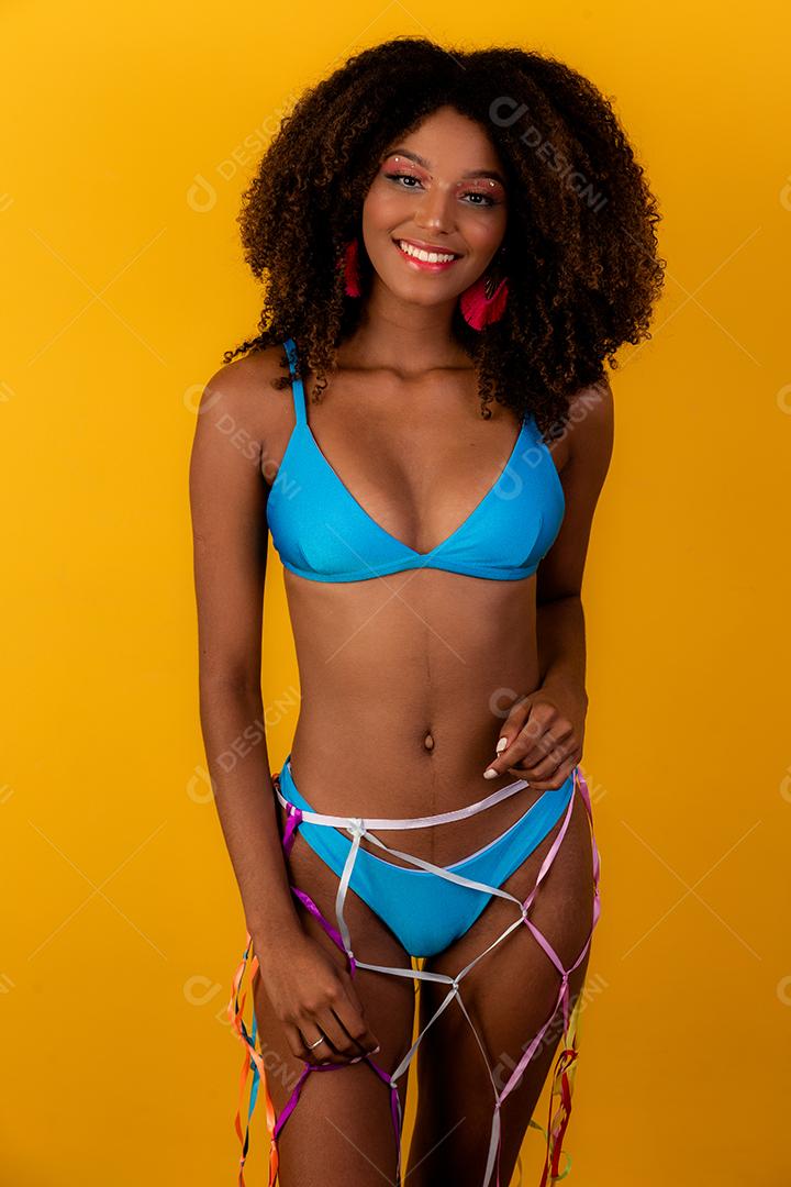 Linda mulher morena sedutora de biquíni sobre um fundo amarelo