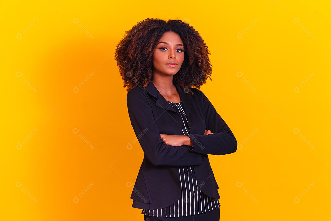 Mulher afro com braços os cruzados em fundo amarelo