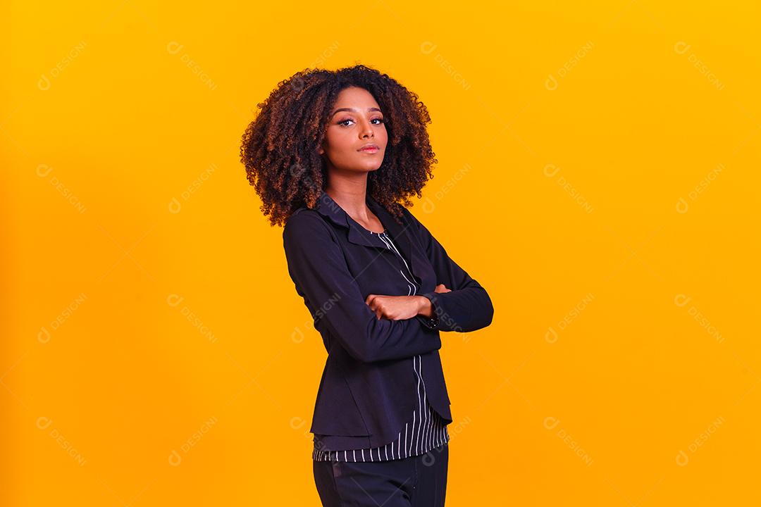 Mulher afro com braços os cruzados em fundo amarelo