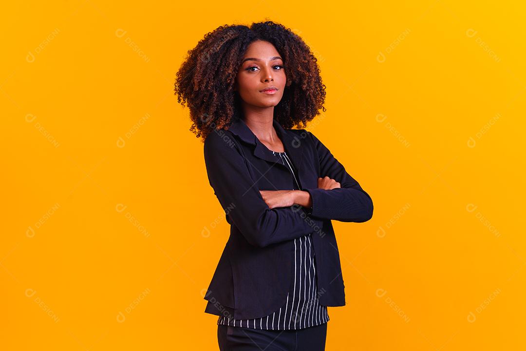 Mulher afro com braços os cruzados em fundo amarelo