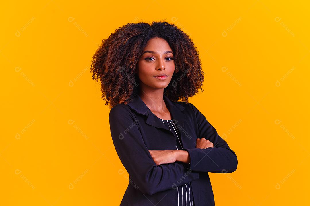Mulher afro com braços os cruzados em fundo amarelo