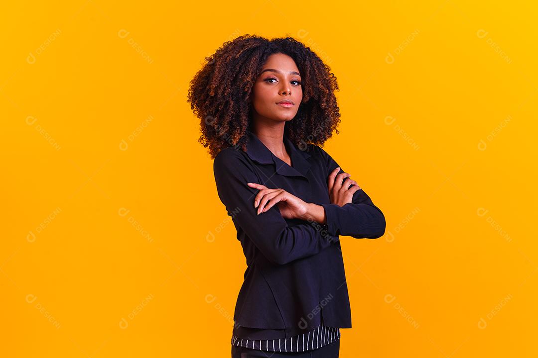 Mulher afro com braços os cruzados em fundo amarelo