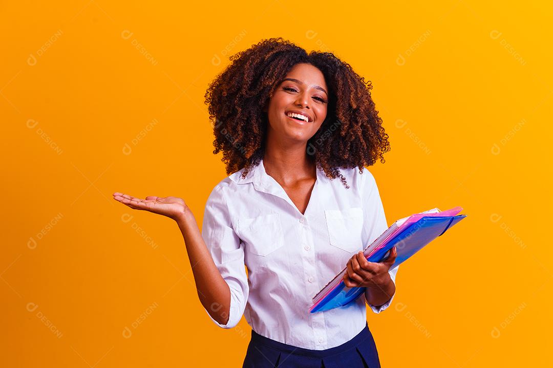 Mulher estudante afro com livros e cadernos nas mãos