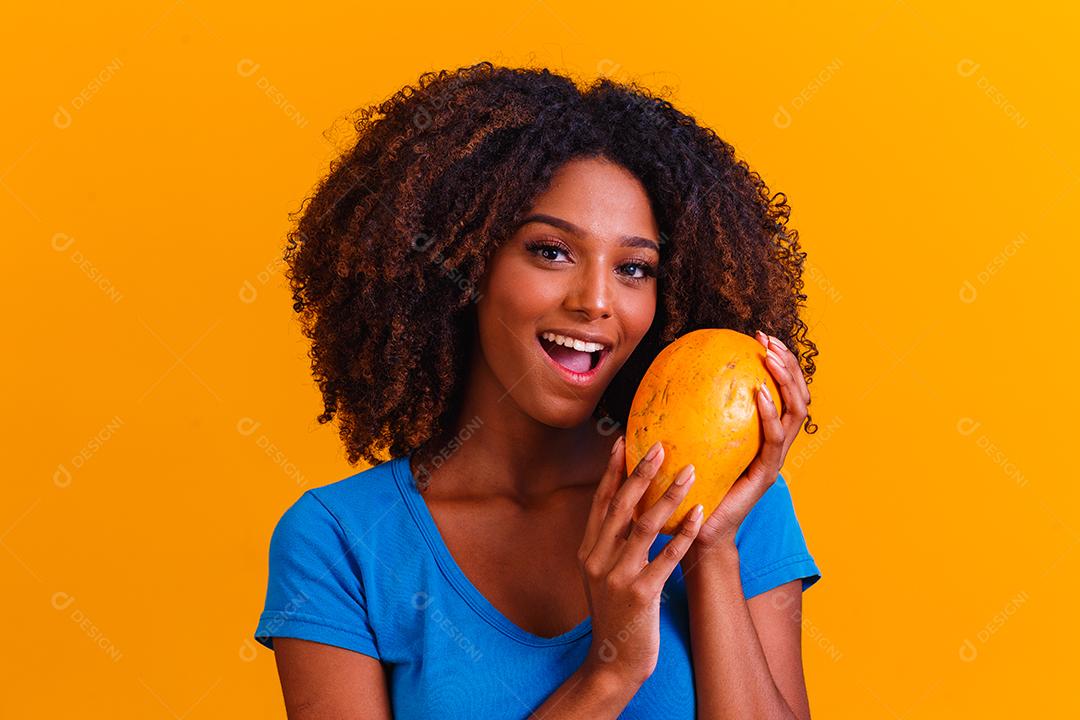 Jovem e bela mulher segurando mamão sobre fundo amarelo isolado