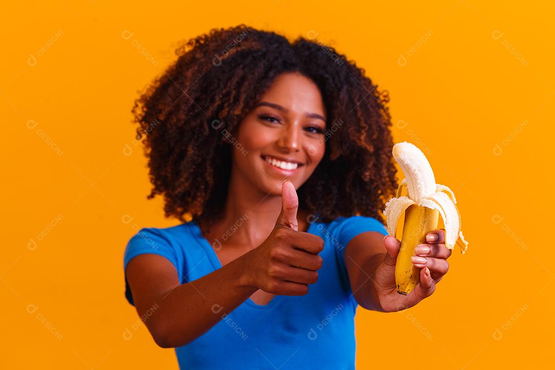 jovem afro comendo banana. Conceito de saúde. Alimentação saudável