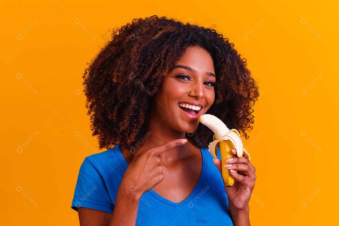 jovem afro comendo banana. Conceito de saúde. Alimentação saudável