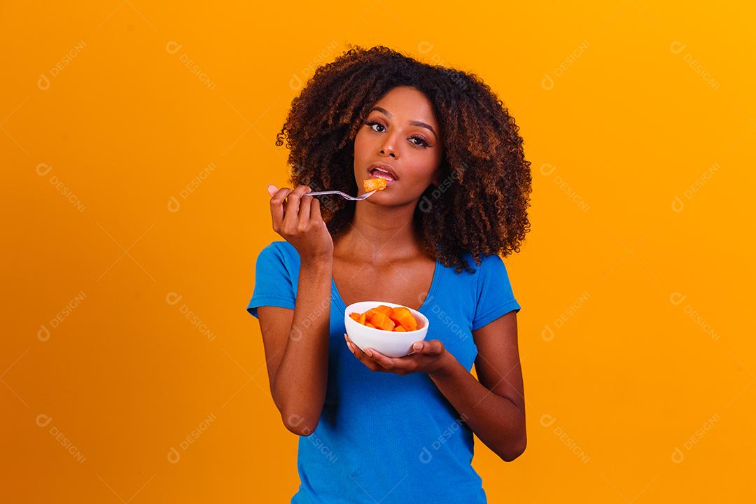 garota afro comendo mamão da tigela. Conceito de alimentação saudável