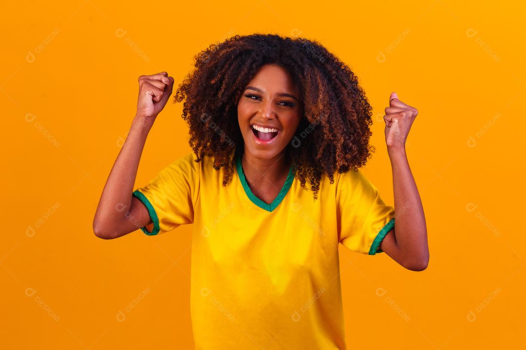 torcedor brasileiro. Fã de mulher brasileira comemorando no futebol ou partida de futebol em fundo amarelo. Cores do Brasil.