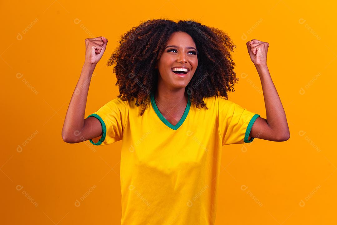 torcedor brasileiro. Fã de mulher brasileira comemorando no futebol ou partida de futebol em fundo amarelo. Cores do Brasil.