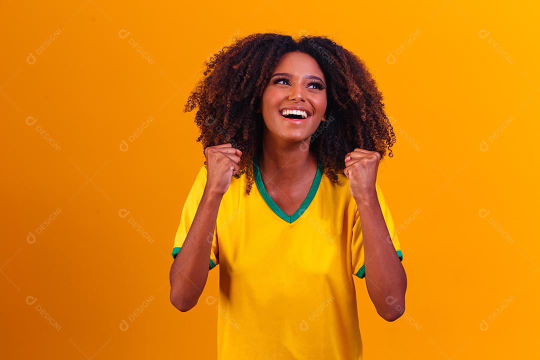 torcedor brasileiro. Fã de mulher brasileira comemorando no futebol ou partida de futebol em fundo amarelo. Cores do Brasil.