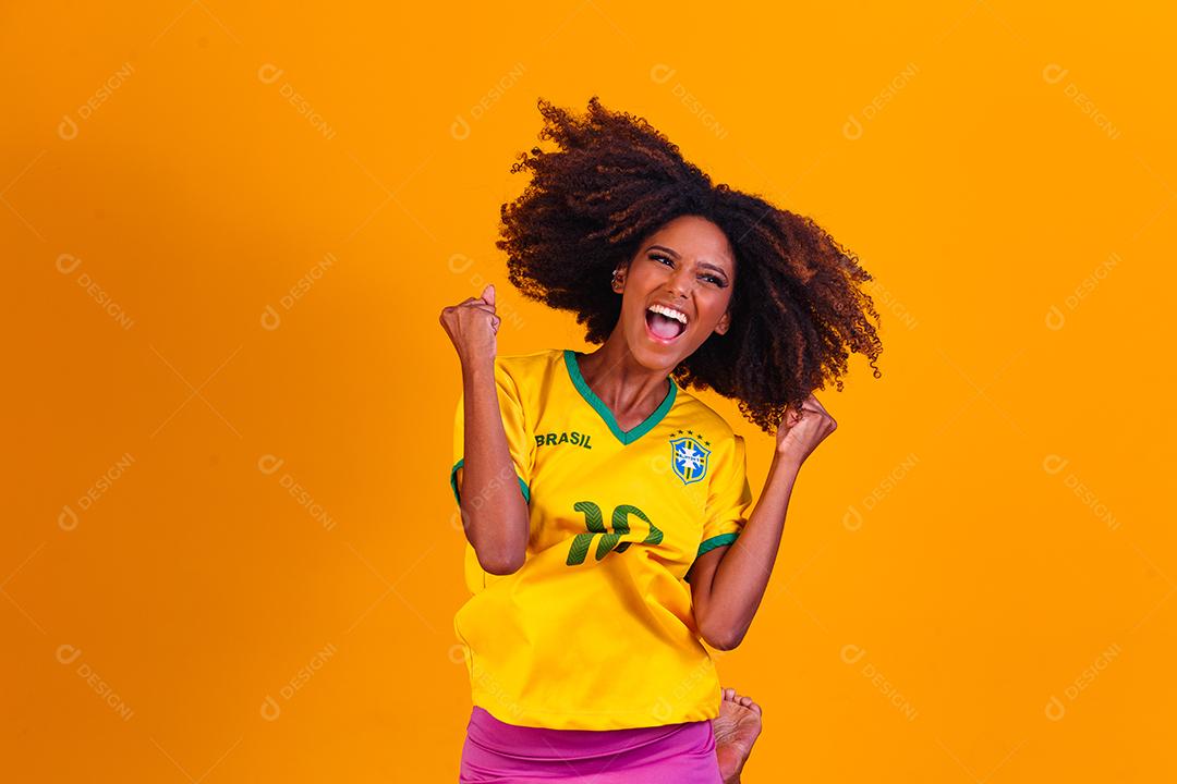 torcedor brasileiro. Fã de mulher brasileira comemorando no futebol ou partida de futebol em fundo amarelo. Cores do Brasil.