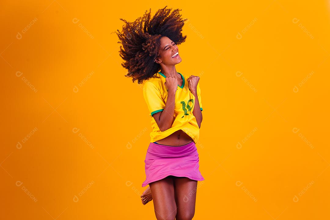torcedor brasileiro. Fã de mulher brasileira comemorando no futebol ou partida de futebol em fundo amarelo. Cores do Brasil.