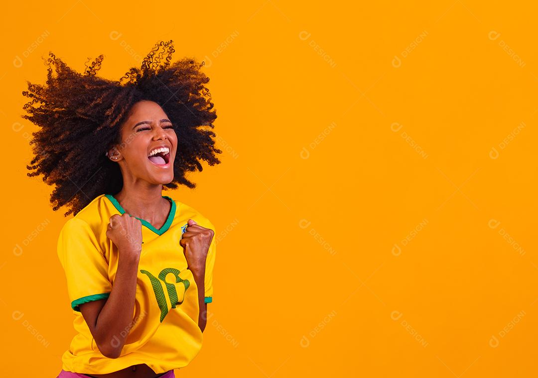 torcedor brasileiro. Fã de mulher brasileira comemorando no futebol ou partida de futebol em fundo amarelo. Cores do Brasil.