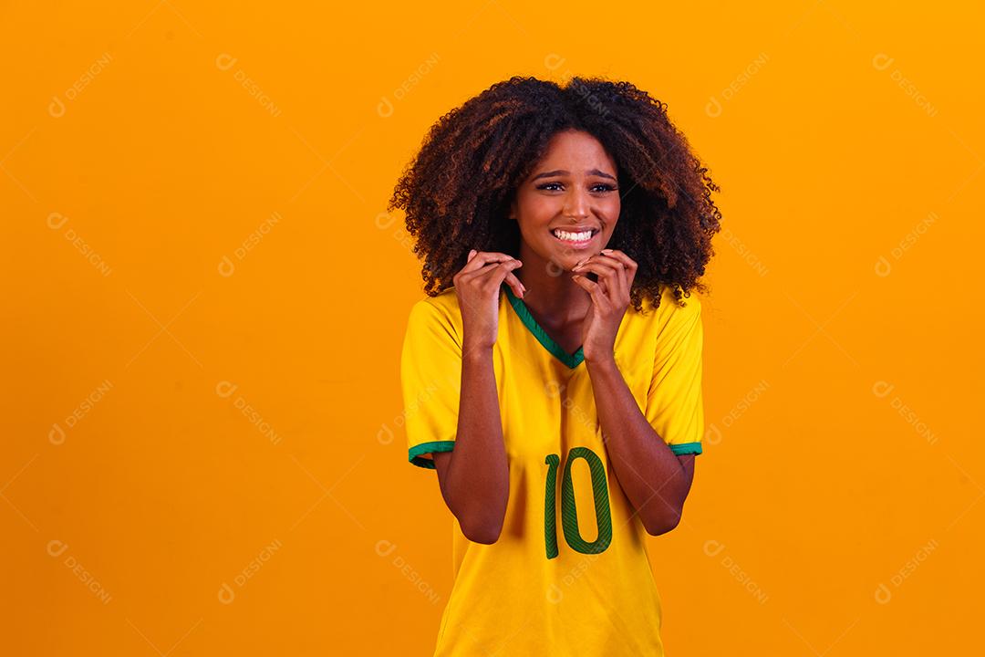 torcedor brasileiro. Fã de mulher brasileira comemorando no futebol ou partida de futebol em fundo amarelo. Cores do Brasil.