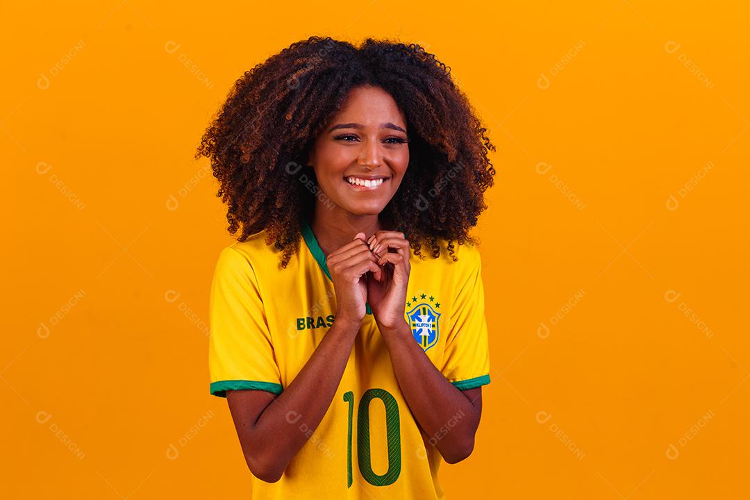 torcedor brasileiro. Fã de mulher brasileira comemorando no futebol ou partida de futebol em fundo amarelo. Cores do Brasil.