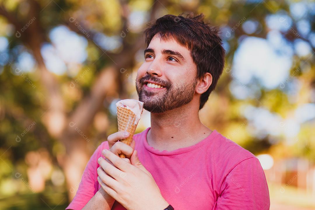 Jovem bonito comendo sorvete no parque