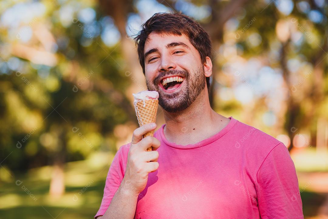 Jovem bonito comendo sorvete no parque