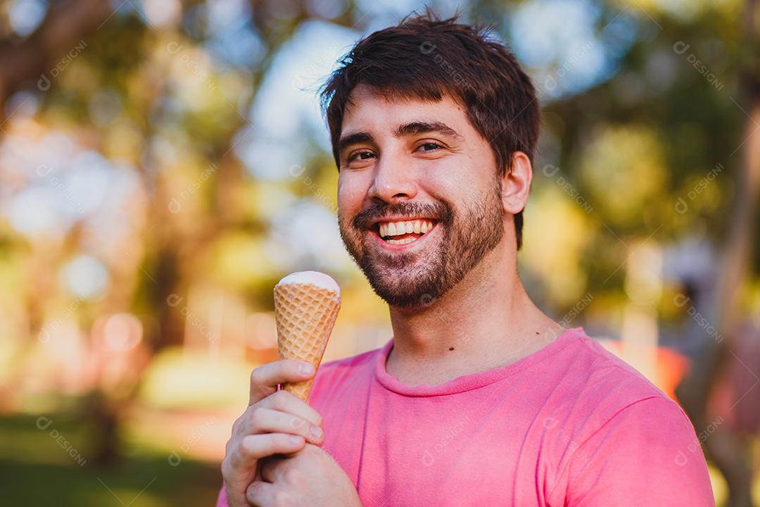 Jovem bonito comendo sorvete no parque